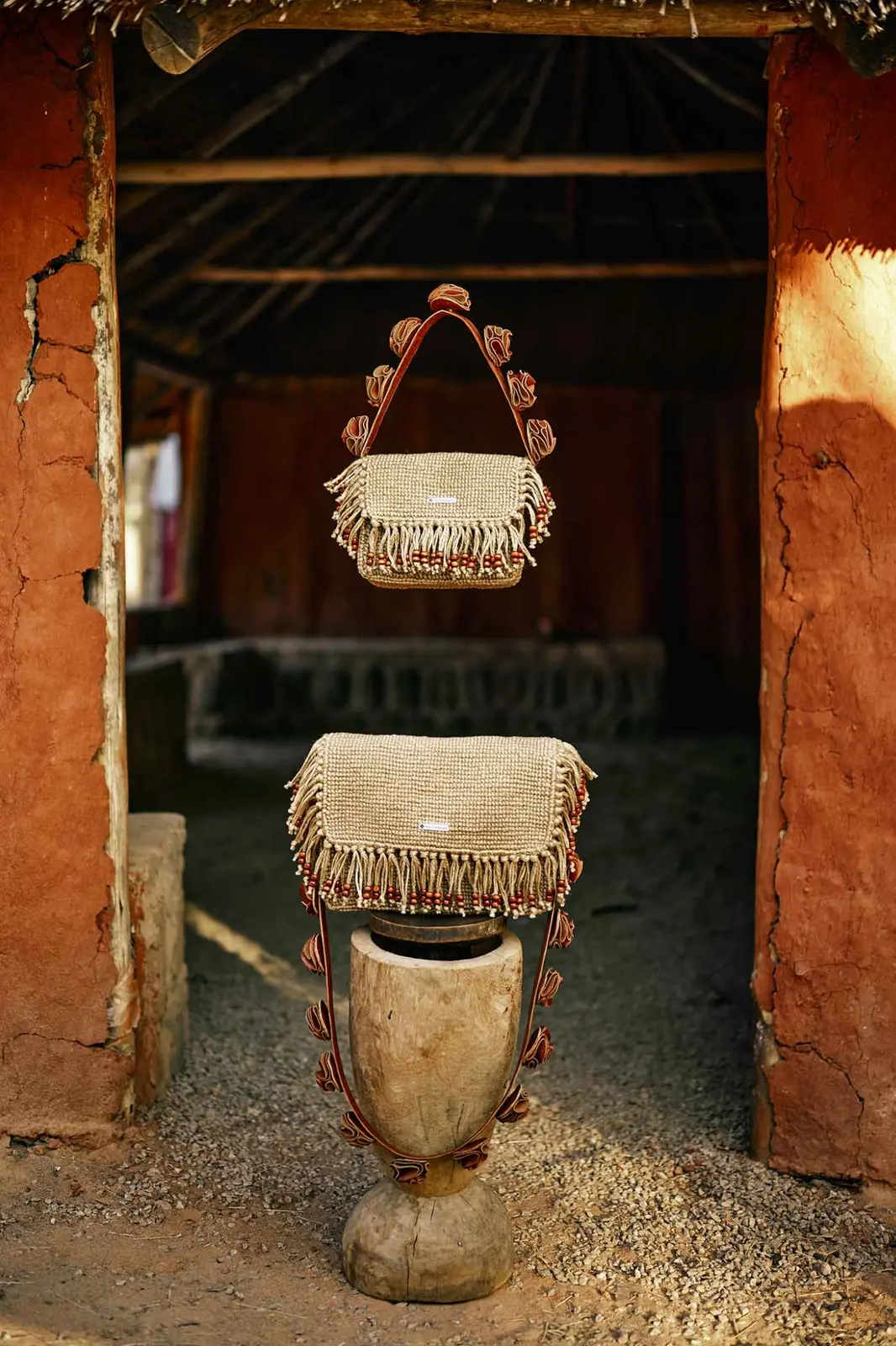 Two handcrafted beaded fringe Nhava bags displayed in a traditional Zimbabwean setting